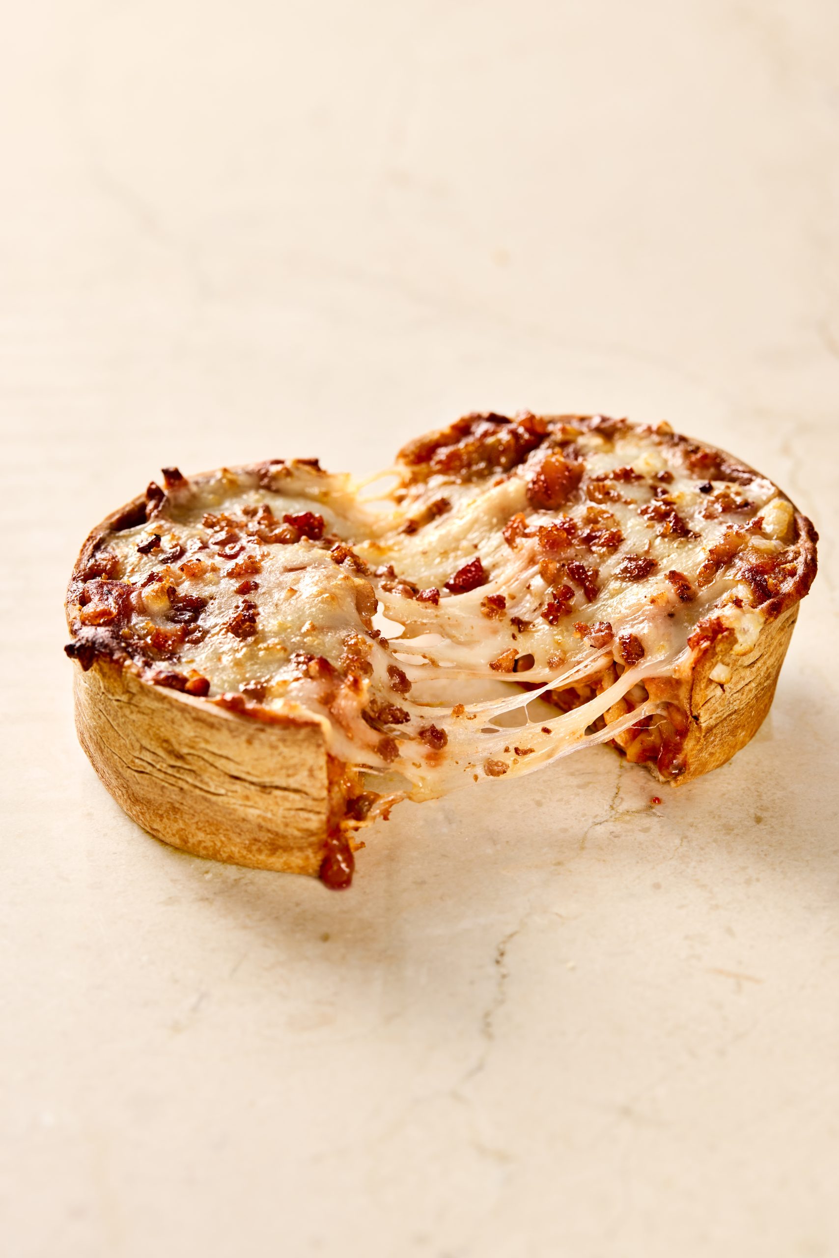Deep-dish bacon pizza with golden crust, tomato sauce and stretchy melted cheese.